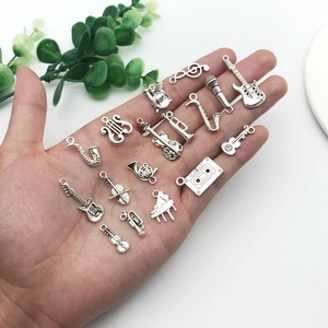 Vintage silver musical instrument charms set for DIY jewelry making displayed on a palm