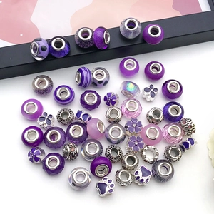 Vista macro di perle di vetro viola e ciondoli in argento per braccialetti fai da te