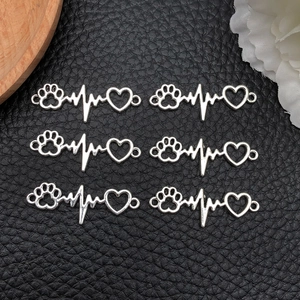 Detailweergave van zilveren hartslagbedeltjes met pootafdruk en hart voor DIY-sieraden
