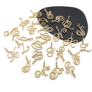 Macro shot of 26 cursive gold-tone metal alphabet pendants with sparkling white rhinestones