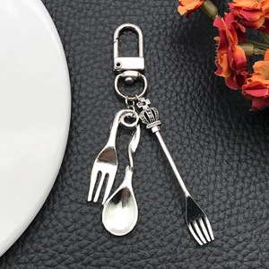 Vintage alloy crown cutlery charms with fork and spoon on black leather background