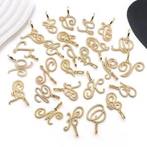 Flat lay of 26 alphabet pendants with cursive design and sparkling zircons set in gold
