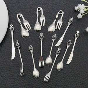 Macro detail of vintage alloy crown-topped spoon, fork, and knife miniature pendants