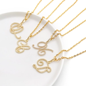 Macro shot of gold alphabet pendants featuring cursive letters with micro pave cubic zirconia