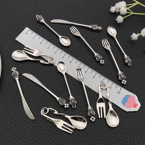 Macro view of vintage silver alloy miniature cutlery pendants with crown detail