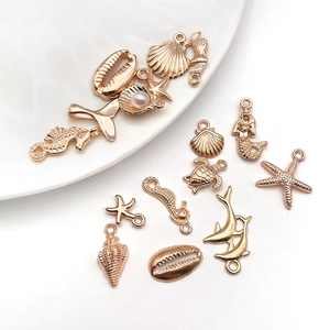 Macro detail of rose gold ocean-themed alloy charms featuring seahorse, starfish and pearl accents