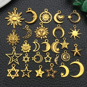 Flat lay macro of sun, moon, and star charms in gold finish on black leather