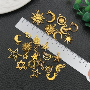Macro view of assorted gold sun moon and star charms with metric ruler for size reference