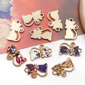 Détail macro de pendentifs chat en alliage avec finition dorée et motifs colorés