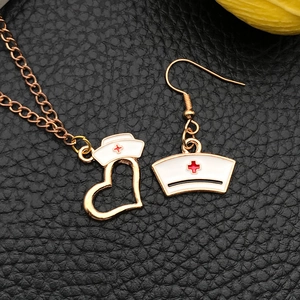 Golden necklace and earring set with red cross nurse cap charm in heart frame