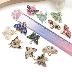 Detailed close-up of 12 colorful butterfly enamel pendants with sizing ruler for DIY jewelry