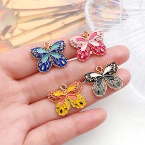 Detail of hand holding colorful butterfly charms in gold plating for DIY jewelry making