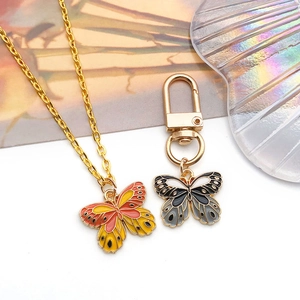 Golden butterfly necklace with orange enamel pendant and a grey keychain accessory