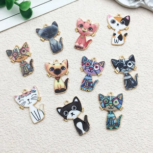 Détail de dix breloques chat assorties en émail coloré sur un fond à texture fine