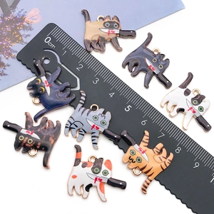 Flat lay of alloy cat charms holding knives in assorted colors with a scale ruler