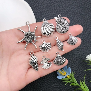 Vintage silver ocean charms set with starfish and shells held in hand for jewelry DIY