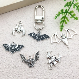Gothic silver bat charms and keychain set on stone background for DIY jewelry making