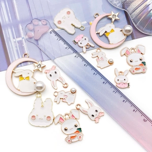 Macro view of bunny and moon enamel charms with pearls for DIY jewelry making