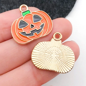 Detalle macro del dije de calabaza de Halloween con frente esmaltado y reverso dorado