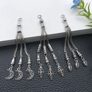 Detailed view of three vintage silver alloy tassel charms with moon and leaf motifs
