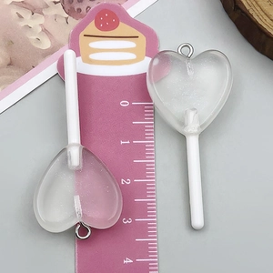 Makroaufnahme von 4,5 cm Herz-Lollipop-Anhängern aus Harz auf einer Messskala für DIY