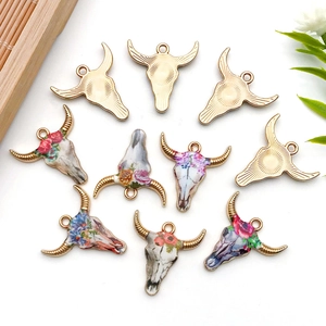 Flat lay of cow head enamel charms with colorful floral patterns for DIY jewelry making