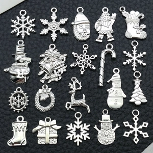 Macro shot of 20 silver Christmas DIY charms including snowflakes and reindeer on black leather