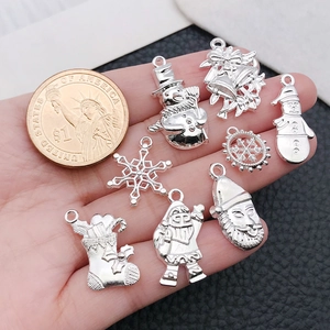 Silver Christmas charms set with snowman and tree next to a coin for size scale