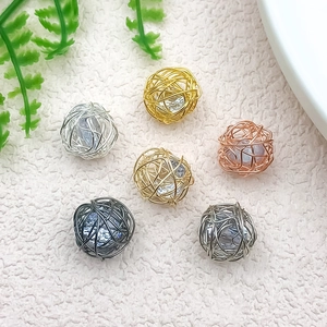 Detailed view of woven wire ball pendants with embedded clear crystals in six metal colors