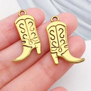 Close-up of gold-plated cowboy boot charms with intricate scroll pattern for DIY jewelry