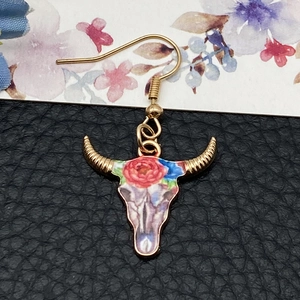 Detail of bohemian bull skull earring featuring red rose paint and golden ear hook