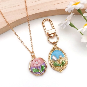 Detail of DIY alloy gold pendants with pink enamel flower and pearl beads on wood surface