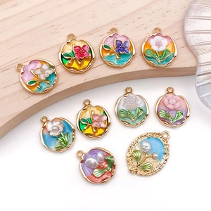 Detailed macro of enamel flower charms with gold-plated alloy and pearl accents
