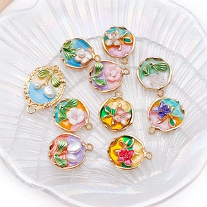 Macro view of floral enamel DIY jewelry charms with gold frames and faux pearl accents