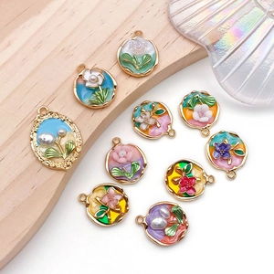 Macro view of colorful enamel flower charms with pearls on a rustic wooden background