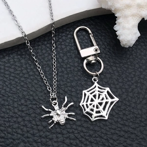 Zilveren spinnenhanger ketting en spinnenweb sleutelhanger set op zwart lederen achtergrond