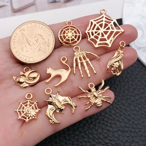 Golden Halloween alloy pendants with spider, bat and skull designs next to a coin