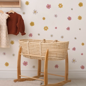Adesivi murali floreali con margherite vintage in una stanza con culla e vestiti da bimbi