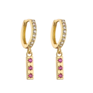Vue macro de boucles d'oreilles huggies dorées avec zircons et pierres roses en étoile