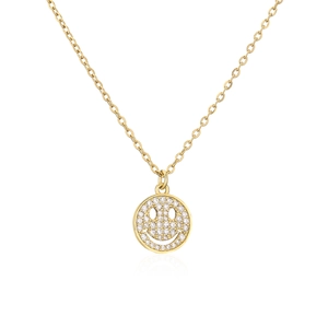Detalle de collar dorado con colgante de cara sonriente y circonitas sobre fondo blanco puro