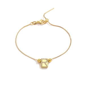 Macro shot of gold letter R pendant with sparkling pavé zircons on an adjustable chain
