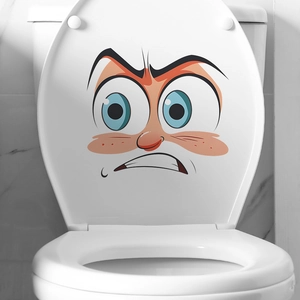 Nahaufnahme eines lustigen Cartoon-Gesicht-Aufklebers auf einem weißen Toilettendeckel