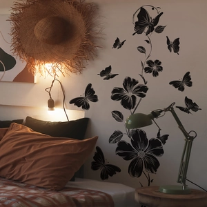 Detailed view of black floral vine wall sticker with butterflies in a cozy bedroom setting