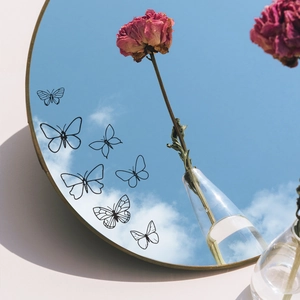 Minimalist butterfly mirror wall decals for home decor shown against a blue sky reflection