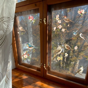 Self-adhesive wall stickers with birds and pink cherry blossom branches on a window glass