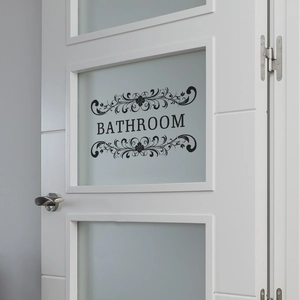 Elegant black vinyl bathroom wall sticker with scroll patterns on a white door