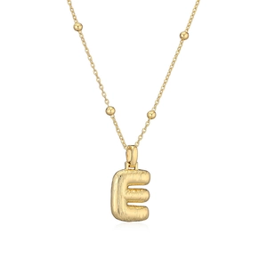 Détail du pendentif lettre E doré avec texture brossée et chaîne satellite élégante