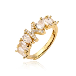 Dettaglio dell'anello dorato con lettera X e zirconi a forma di cuore e goccia d'acqua