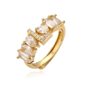Dettaglio dell'anello dorato LOVE con zirconi a forma di cuore e goccia scintillante