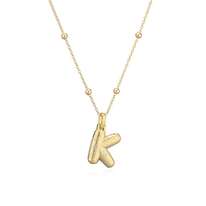 Détail du collier lettre K dorée avec texture en métal brossé et chaîne à petites boules